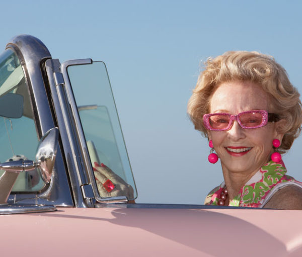 Older woman driving convertible car.